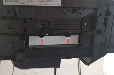 프린터 바닥에 있는 흰색 덮개 부분의 탭을 당겨 여는 예시 화면