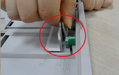 용지 너비 가이드를 손으로 누르는 화면