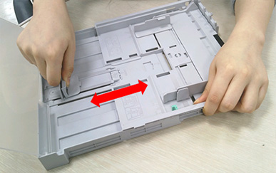 용지 길이 가이드를 눌러 잡고 이동시키는 화면